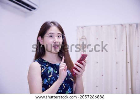 Asian woman touching her cell phone indoors