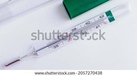 Glass Mercury thermometer with Celsius degree. Fever and healthcare concept. Closeup. Royalty-Free Stock Photo #2057270438