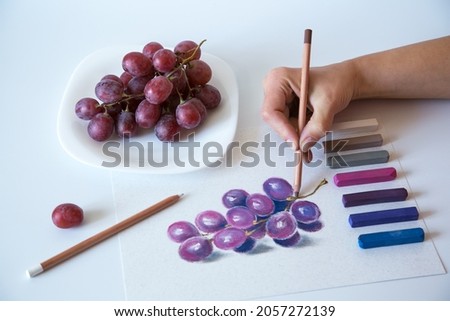 Soft pastel painting of grapes. The process of soft pastel drawing with an artist's hand. Painting on quarantine.