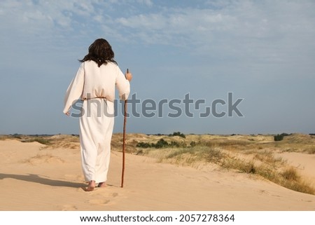 Jesus Christ walking with stick in desert, back view. Space for text Royalty-Free Stock Photo #2057278364