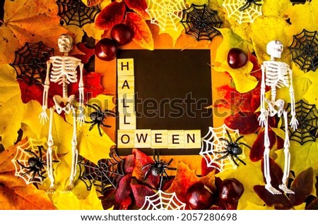 Happy autumn holiday Halloween concept.  Colored background decorated with leaves and two skeletons in the middle, place for text and the inscription Halloween.  Photo view from the top.  Baner, postc
