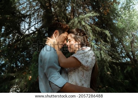 Attractive interracial couple asian european hugging under Dramatic light at the park