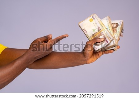 hand holding a lot of cash and pointing to it, naira currency