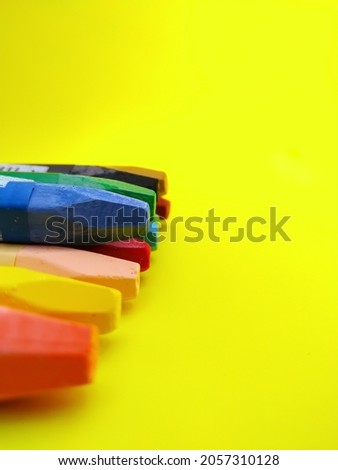 children's multi-colored wax crayons for drawing, on a yellow background