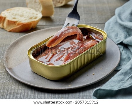 canned anchovy fillets and slices of baguette on wooden kitchen table Royalty-Free Stock Photo #2057315912