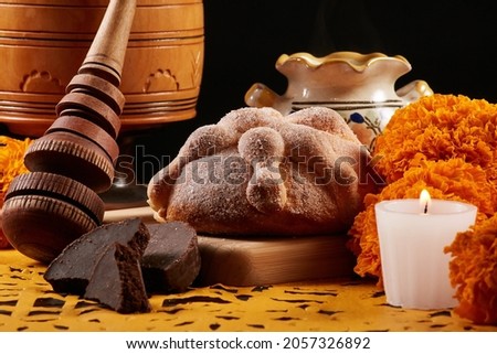 Offering for the Day of the dead with bread of the dead, chocolate, a traditional turned wood whisk to make hot chocolate and a typical clay cup Mexican marigold and a candle over yellow festive paper Royalty-Free Stock Photo #2057326892