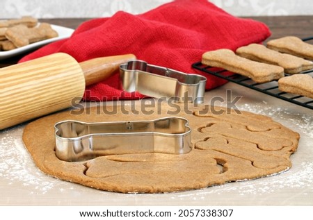 Setting of a rolling pin and dog bone cookies cutters. Selective focus on cookie cutter and dough. Royalty-Free Stock Photo #2057338307