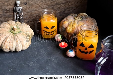 Fresh orange juice in glasses with jack o'lantern face and jelly eyeballs. Halloween concept.