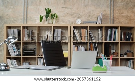No people in a casual workplace, desk, and president chair in Architecture and Interior Design office, models, books, accessories, and equipment in the bookshelf decorate in modern-loft style. Royalty-Free Stock Photo #2057361152