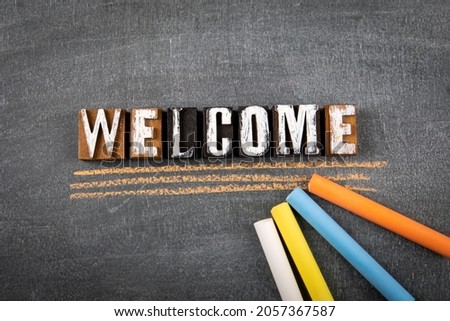 Welcome. Different colored chalks on a black chalk board.