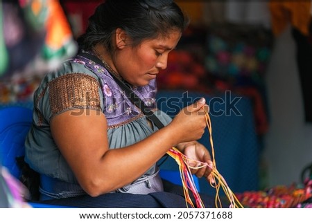 young Mexican woman embroidering typical regional blouses and shirts