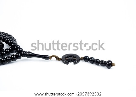 Prayer beads in shiny black on a white background.  Prayer bead with crescent and star pendulum