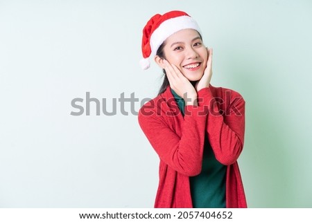 Young Asian woman wearing christmas hat on green background, x-mas concept