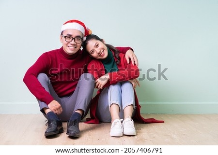 Young Asian couple posing on green background with christmas concept