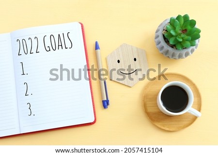 Business concept of top view 2022 goals list with notebook, cup of coffee over wooden desk Royalty-Free Stock Photo #2057415104