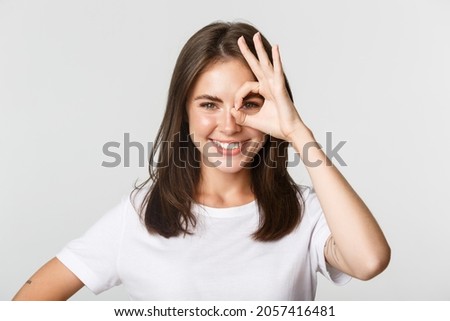 Close-up of attractive confident girl smiling satisfied and showing okay gesture over eye