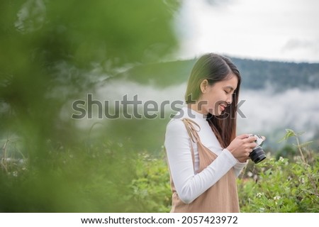 Attractive asian woman taking photo with retro film camera among the nature at countryside in the morning