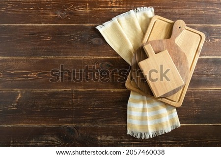 Empty wooden cutting boards on a yellow cotton towel on a brown plank surface with copy space. Wood, country theme. Concept for advertising cooking courses, food blog, kitchen utensils, menus, recipes