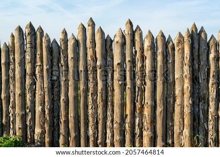 Wooden palisade made of logs. Log wooden fence. Sharp stakes in the ground. Royalty-Free Stock Photo #2057464814