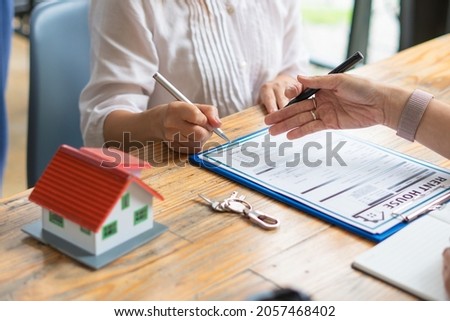 Customers interested in buying a home sign a signature to enter into a home purchase contract with a real estate agent. Mortgage loan approval home loan and insurance concept.