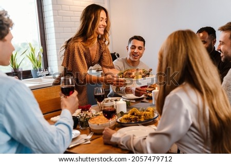 Multiracial happy friends eating turkey during thanksgiving dinner at home