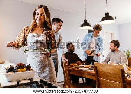 White couple cooking turkey for thanksgiving dinner with their friends at home