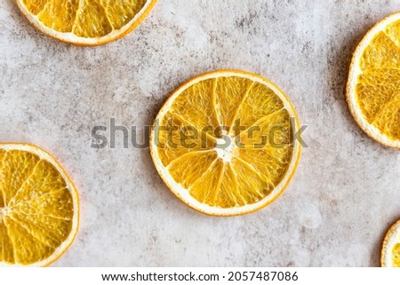 Pattern with slices of dried orange on light concrete background. Food background. Top view. Flat lay. Selective focus.
