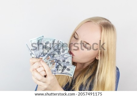 Close-up of a girl sniffing money. Madness and greed from currency. The concept of corruption and getting money at any cost. Squeeze and toss US dollars. Wild thirst for profit