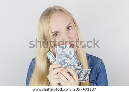 Close-up of a girl sniffing money. Madness and greed from currency. The concept of corruption and getting money at any cost. Squeeze and toss US dollars. Wild thirst for profit