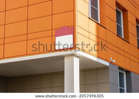 Mock up sign on a modern building with orange wall panels. Public building