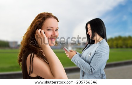 two happy women and using the phone on a street