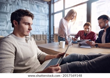 Business team working at desk in office. Concept of successful people. Business and entrepreneur lifestyle. Young men and girl discussing about business document. Man watching something on laptop