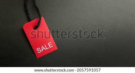 Black Friday Sale or Discount banner. Red clothes tag over black background. Modern minimal design with space for text. Template for promotion, advertising, web, social and fashion ads. High quality Royalty-Free Stock Photo #2057591057