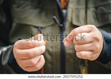 Close up shot of young fisherman's hands tying a fly for fishing. Fly fishing concept. Royalty-Free Stock Photo #2057591252