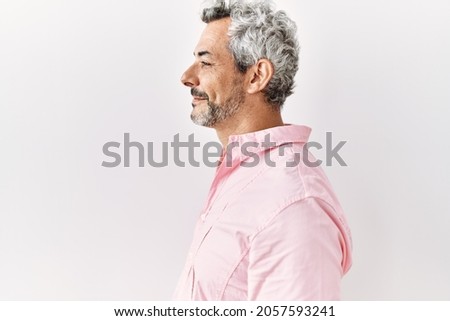 Middle age hispanic man standing over isolated background looking to side, relax profile pose with natural face with confident smile.  Royalty-Free Stock Photo #2057593241