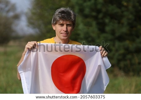 Flag of Japan in the hands of a man of Caucasian race