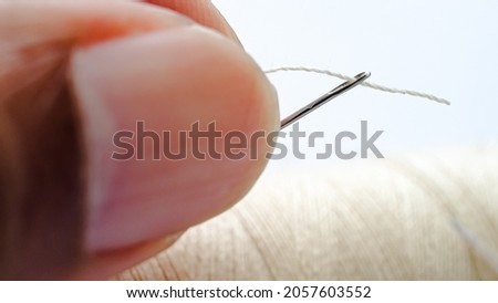 close up hand passing a thread in needle 