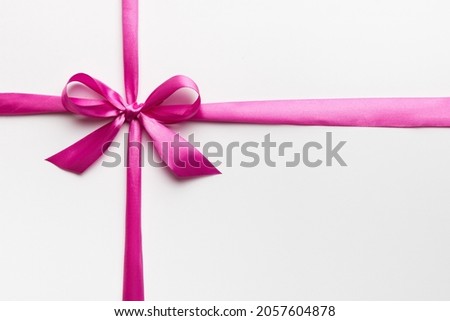 Top view of purple ribbon rolled and pink bow isolated on colored background. Flat lay with copy space.