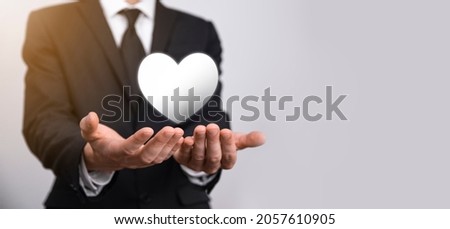 Male hand holding heart , like icon on blue background. Kindness, charity, pure love and compassion concept.Banner with copy space.