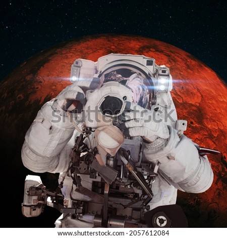 Astronaut photographer with a camera taking pictures against the background of the red planet Mars. Space Mission Concept 