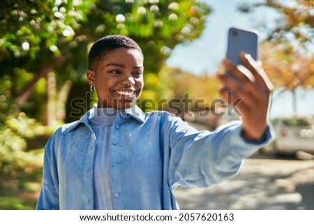 Young african american woman smiling happy making selfie by the smartphone at the city