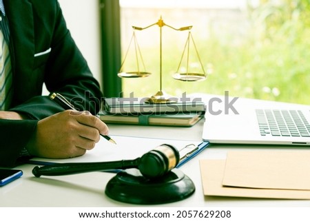 Judge or lawyer working on paperwork behind the weight of justice, a male lawyer working at a desk in an office. Emphasis is placed on the level of justice that the hammer is placed in front of the sc