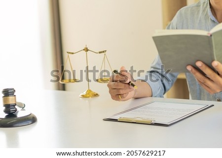 Judge or lawyer working on paperwork behind the weight of justice, a male lawyer working at a desk in an office. Emphasis is placed on the level of justice that the hammer is placed in front of the sc