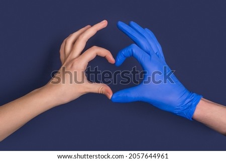 Doctor and patient hands in protective gloves showing heart symbols in hospital. gratitude of the patient. Heart shaped hands. Health care, charity, protection from COVID-19