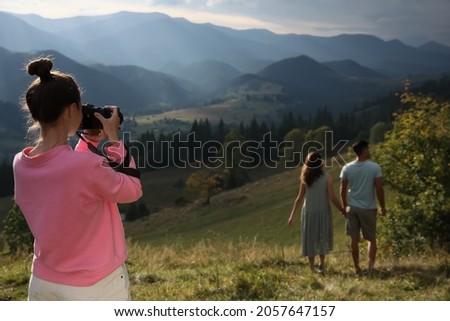 Professional photographer taking picture of couple in mountains