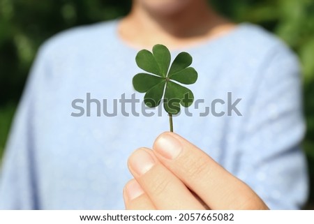Woman holding green four leaf clover outdoors, closeup Royalty-Free Stock Photo #2057665082