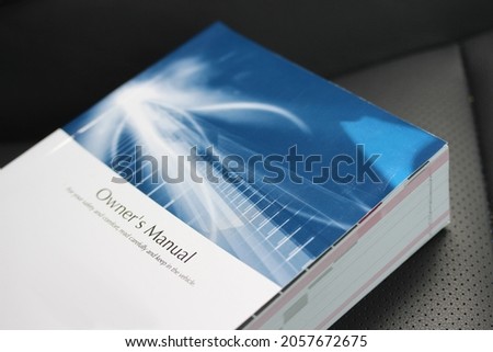 Vehicle owners manual lying on a black leather seat Royalty-Free Stock Photo #2057672675