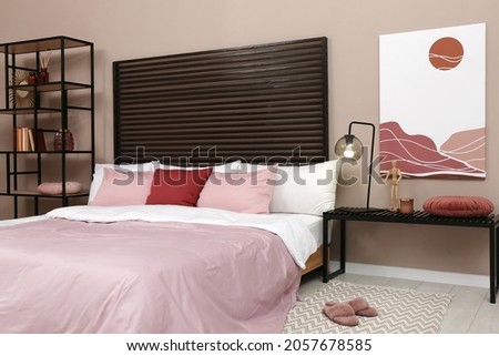 Large comfortable bed near beige wall in room. Interior design