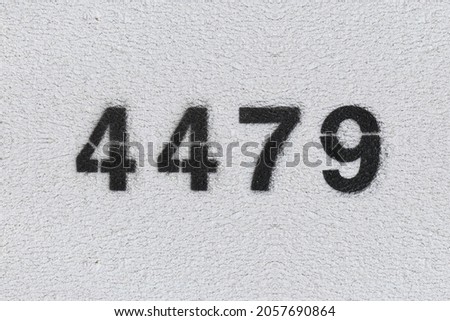 Black Number 4479 on the white wall. Spray paint. Number four thousand four hundred and seventy nine.