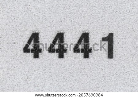 Black Number 4441 on the white wall. Spray paint. Number four thousand four hundred and forty one.